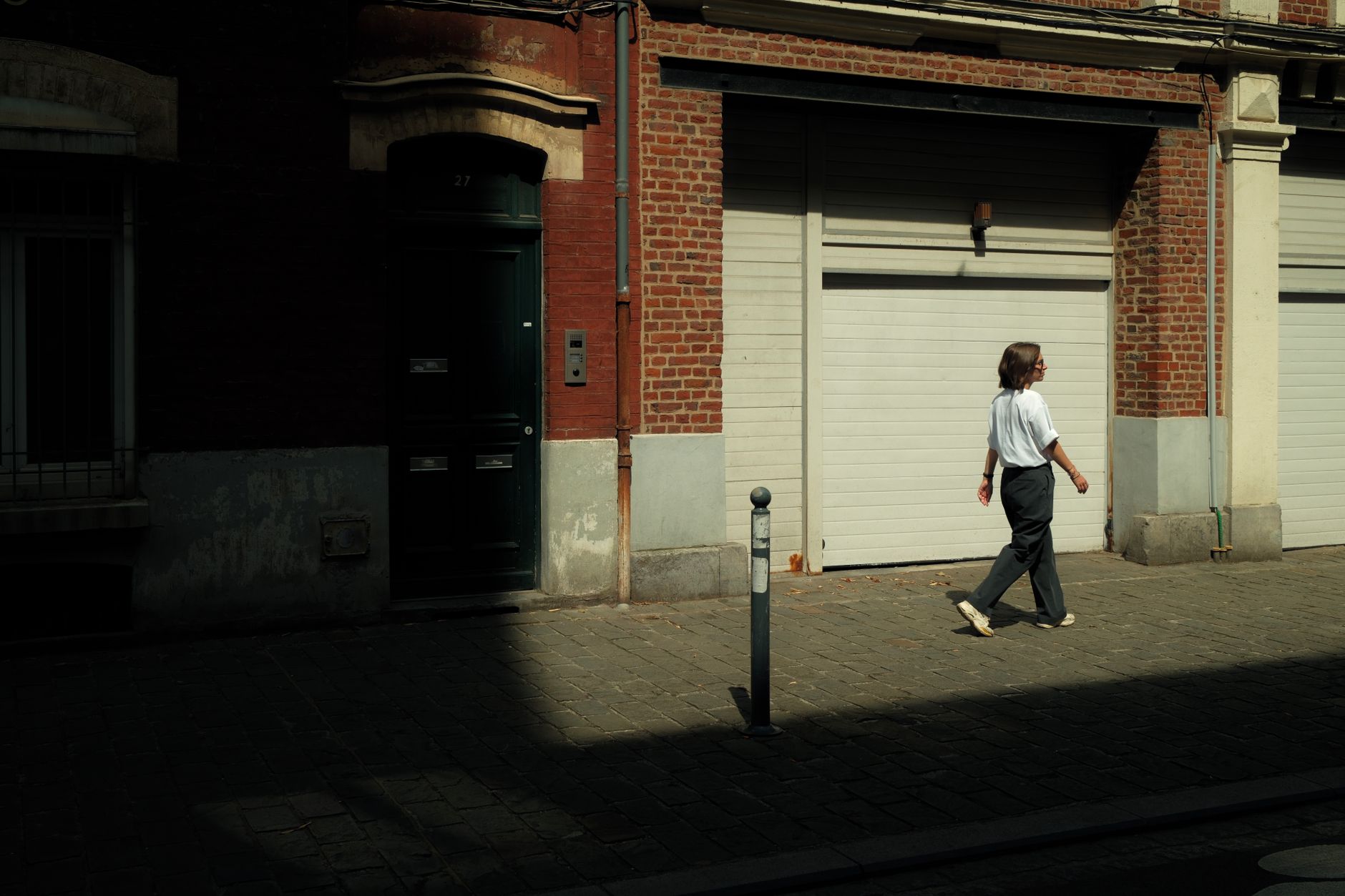 A woman walks along a sunlit street in Lille, France.
