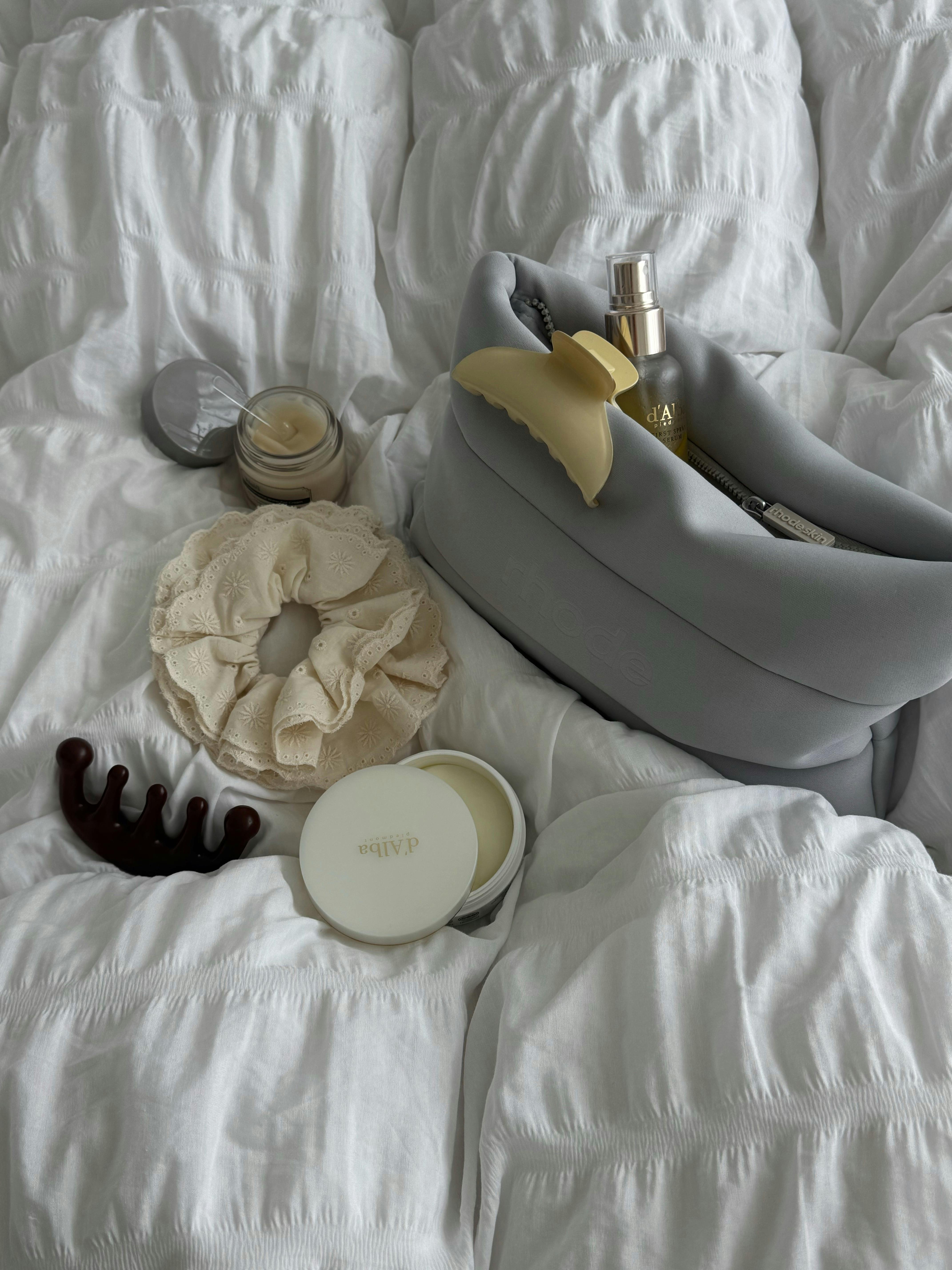 Elegant bedroom essentials laid out on soft white bedding, creating a cozy and luxurious vibe.