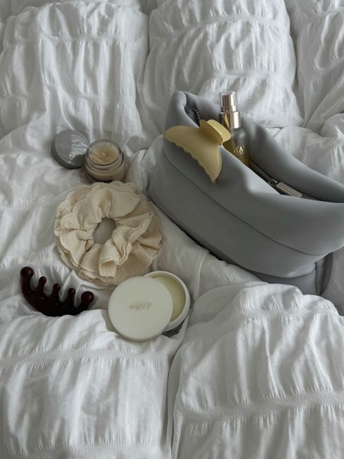 Free Elegant bedroom essentials laid out on soft white bedding, creating a cozy and luxurious vibe. Stock Photo