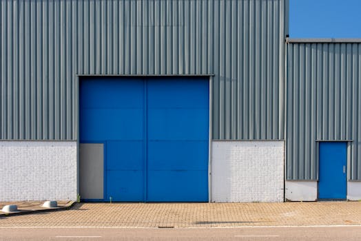 Front view of a blue and gray metal warehouse exterior with large doors.