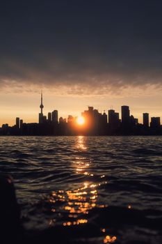 Stunning view of Toronto skyline with sunset reflection on Lake Ontario waters.