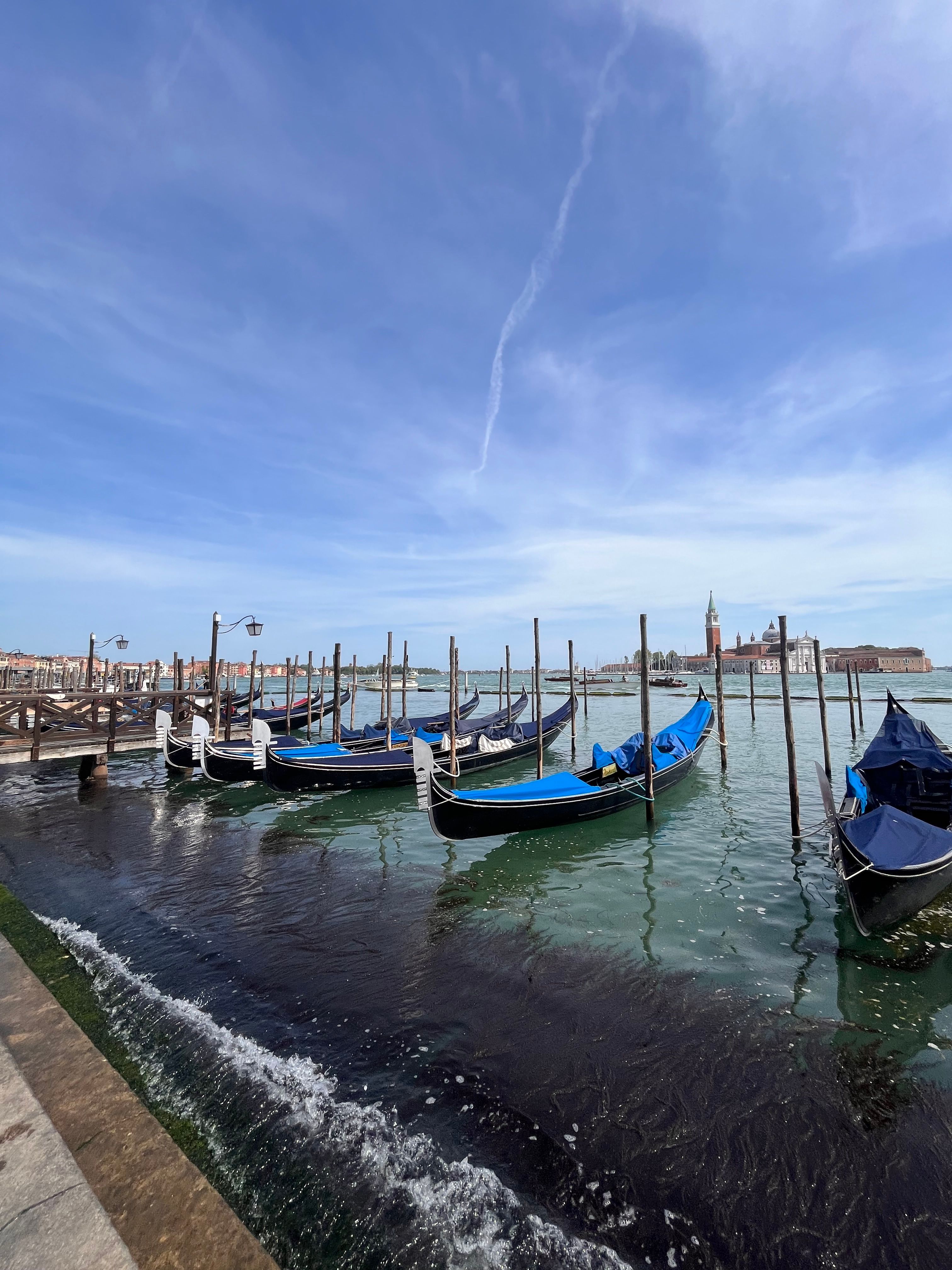 Beautiful gondolas moored along the Grand Canal in Venice with a clear blue sky.