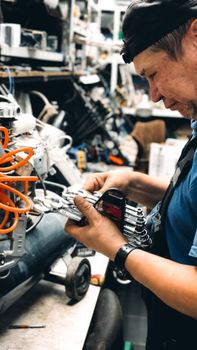 Experienced male technician working on complex machinery in workshop.