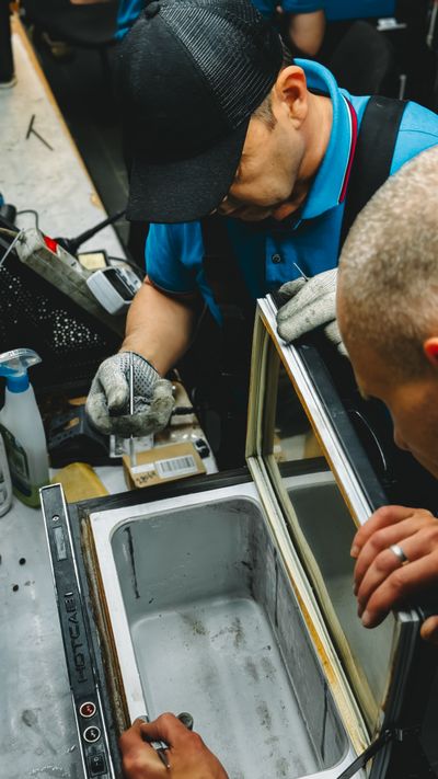 Two technicians repairing an industrial freezer