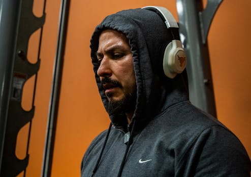 Athlete in hoodie and headphones focusing during workout at the gym, emphasizing determination and dedication.
