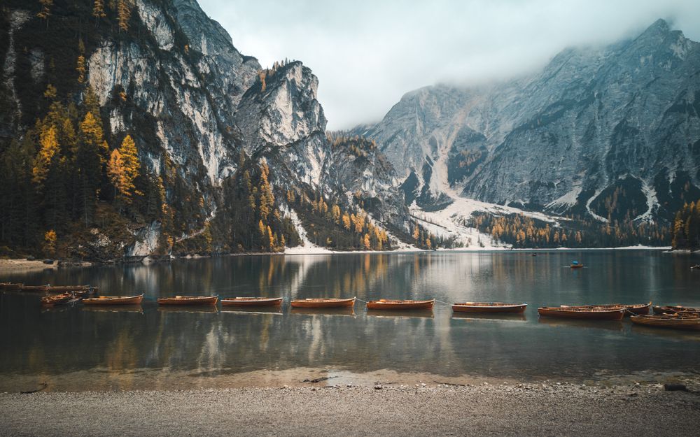 Lacul Braies liniștit, cu bărci și pădurea de pe maluri