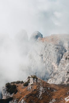 A serene view of mist-covered rocky mountains in Veneto, Italy.