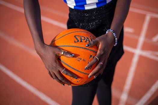 Close-up view of hands gripping a basketball indoors on a sports track.