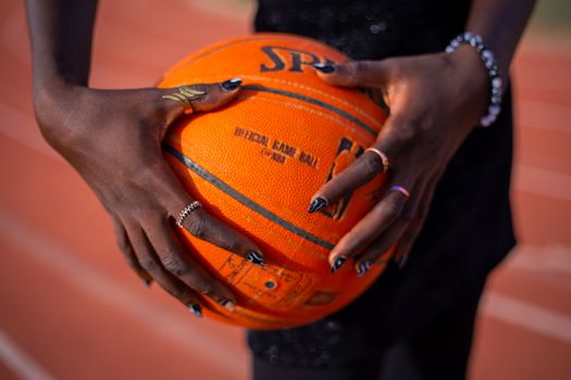 Close-up shot of hands holding a basketball on an outdoor sports track.