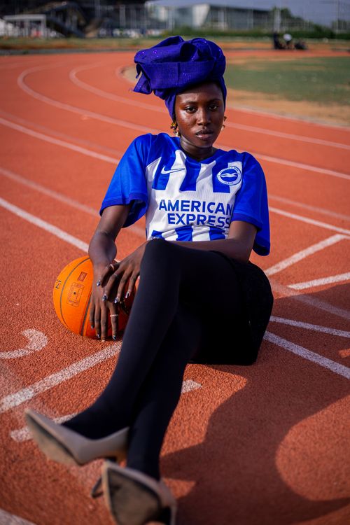 Free Confident woman in sports jersey posing on the running track with a basketball. Stock Photo