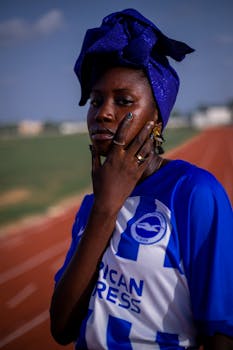 Woman wearing a blue headwrap and sports jersey on a sunny day.