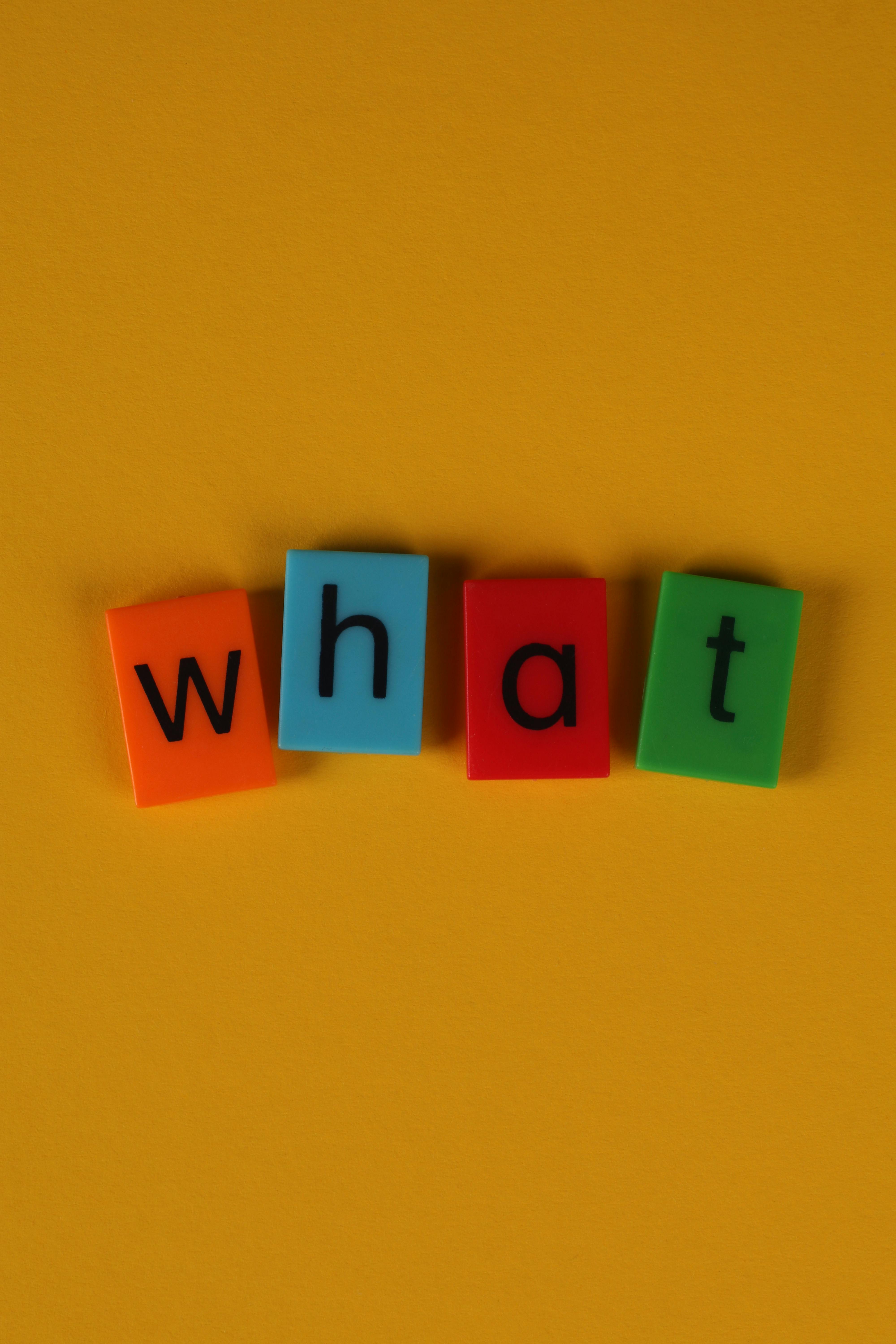 gratis Kleurrijke letterblokken met de tekst 'what' op een gele achtergrond, ideaal voor educatieve en creatieve content. Stockfoto