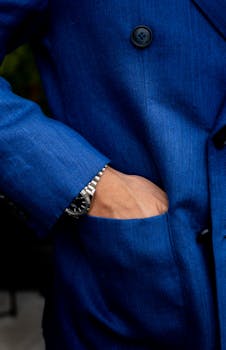 Close-up of an elegant blue blazer with a luxury watch peeking from the pocket.