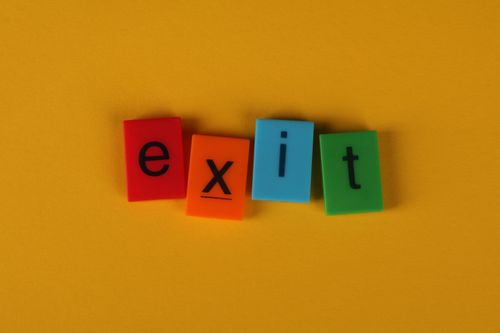 Free Vibrant exit sign with colorful letters on a solid yellow background, ideal for creative design concepts. Stock Photo