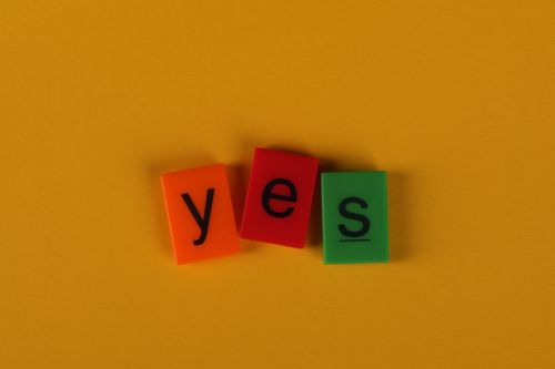 Free Brightly colored tiles spell 'yes' on a vibrant yellow background. Stock Photo