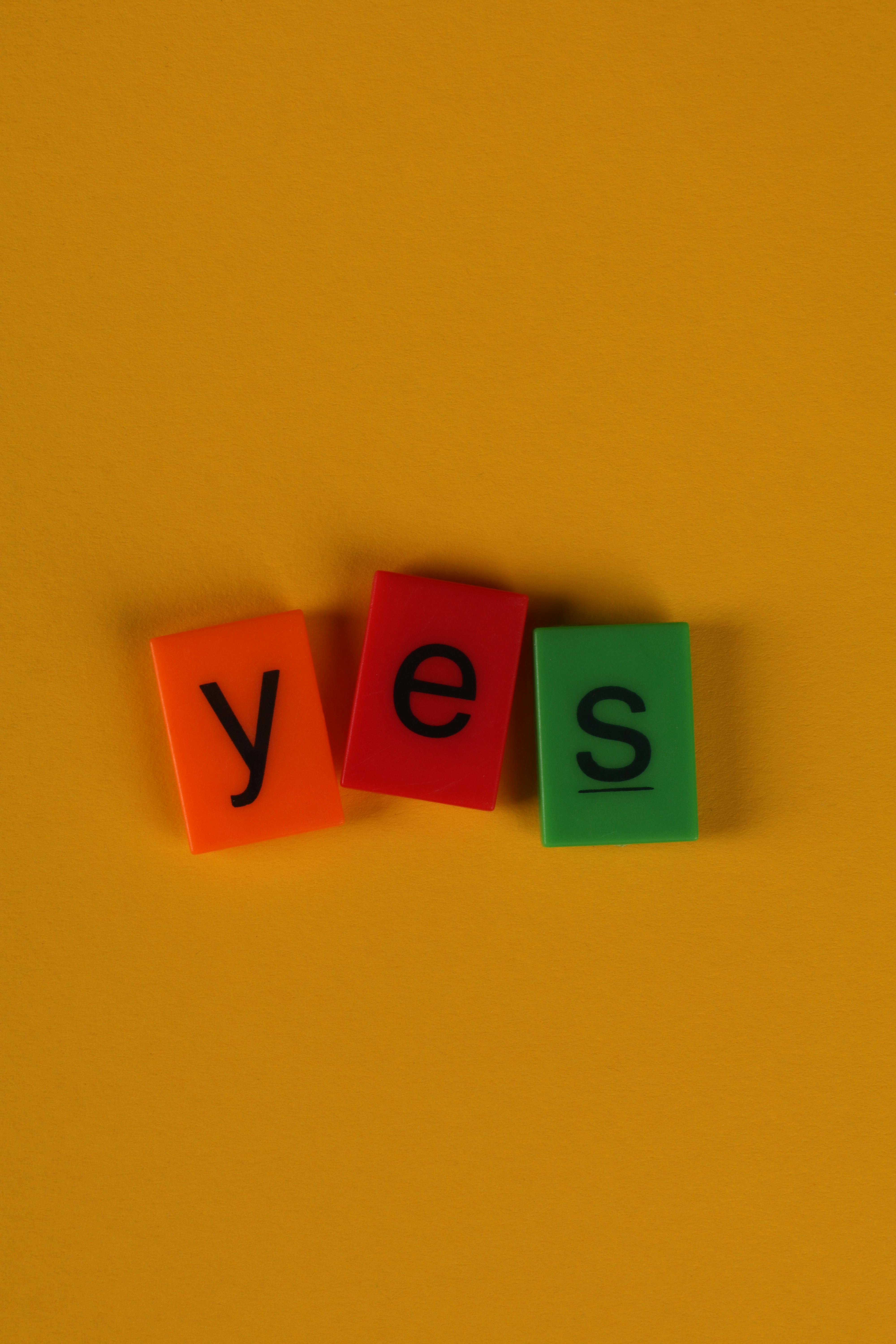 Brightly colored blocks spelling 'yes' on a vibrant yellow background.