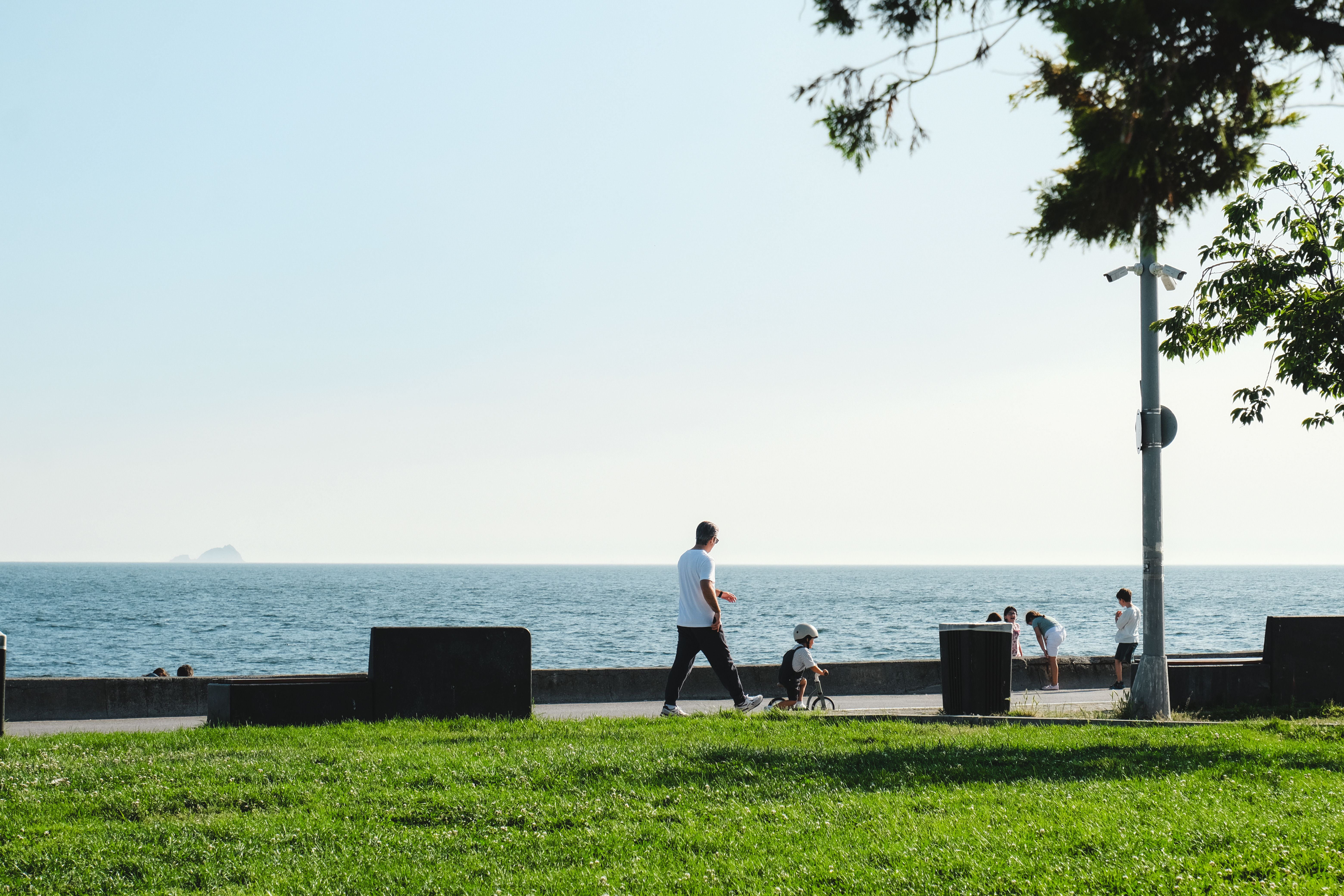 A man walks with a child along a scenic seaside promenade on a sunny day. — Trójmiasto