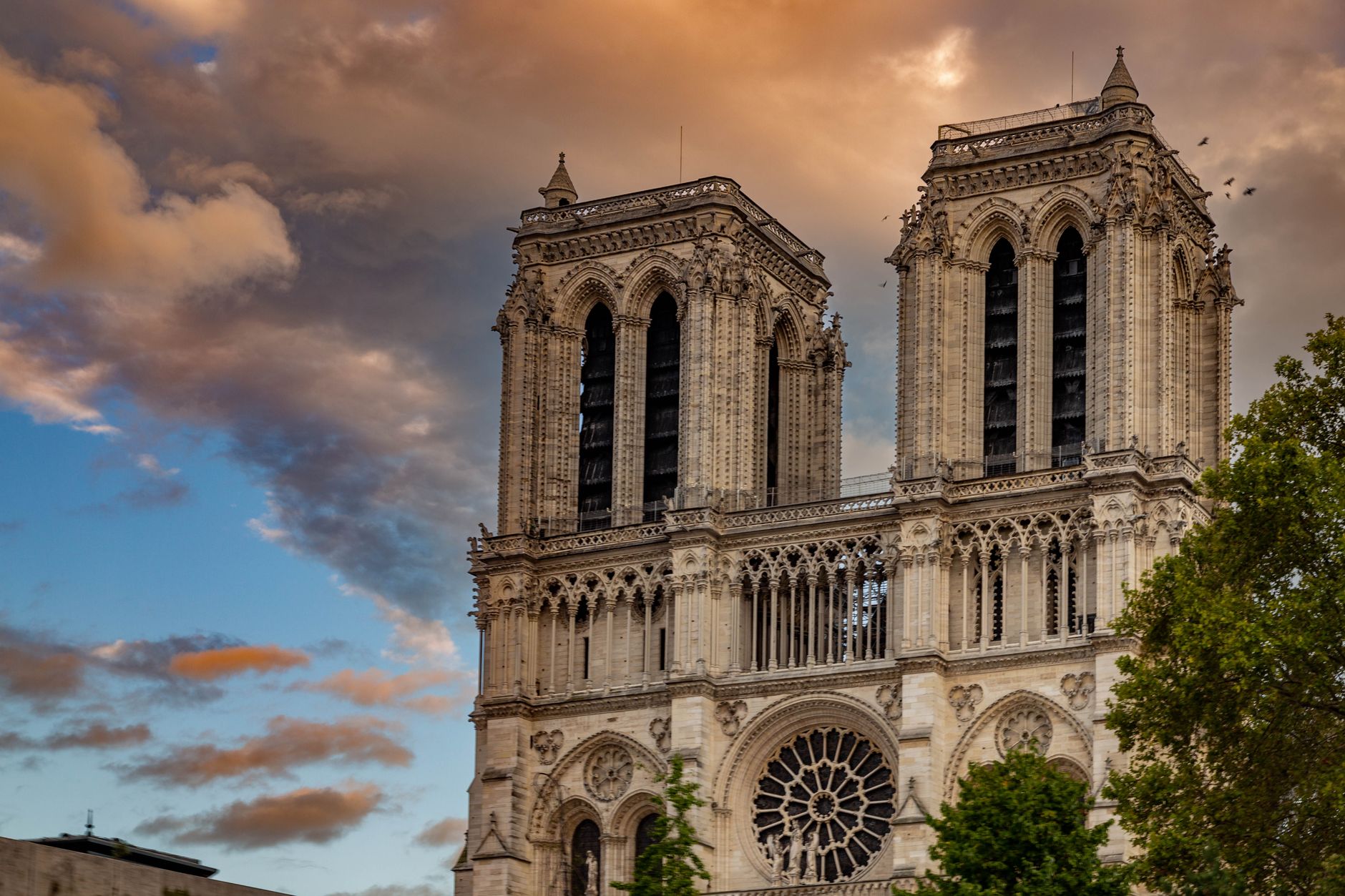 The iconic Notre-Dame Cathedral captured at sunset with dramatic skies in Paris.