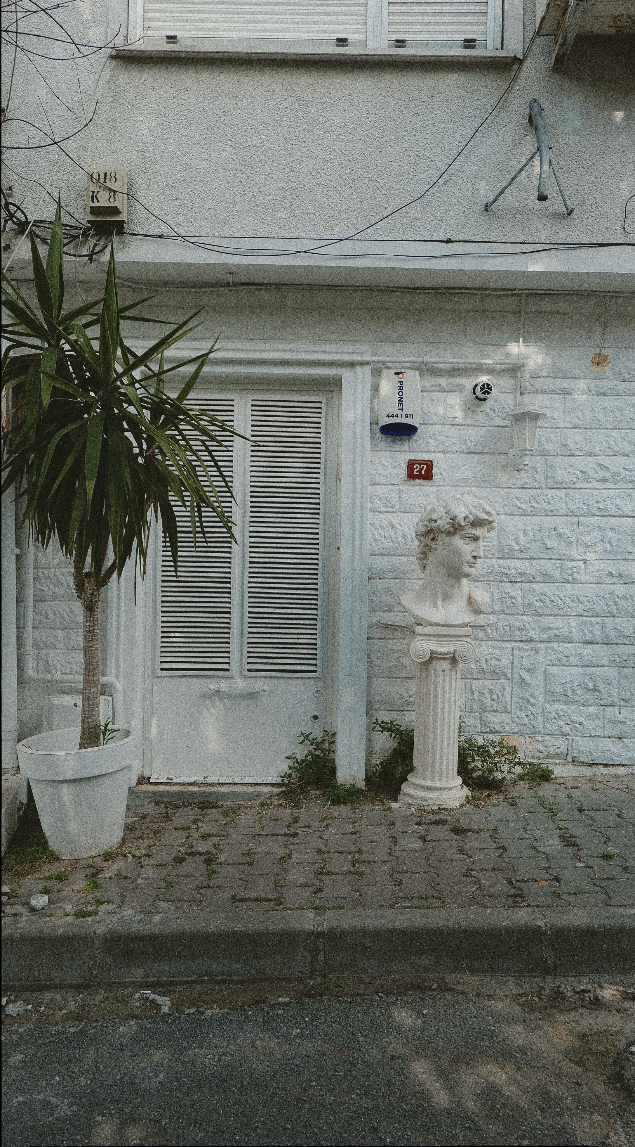 Elegant urban front door with white shutters and classical bust decoration.