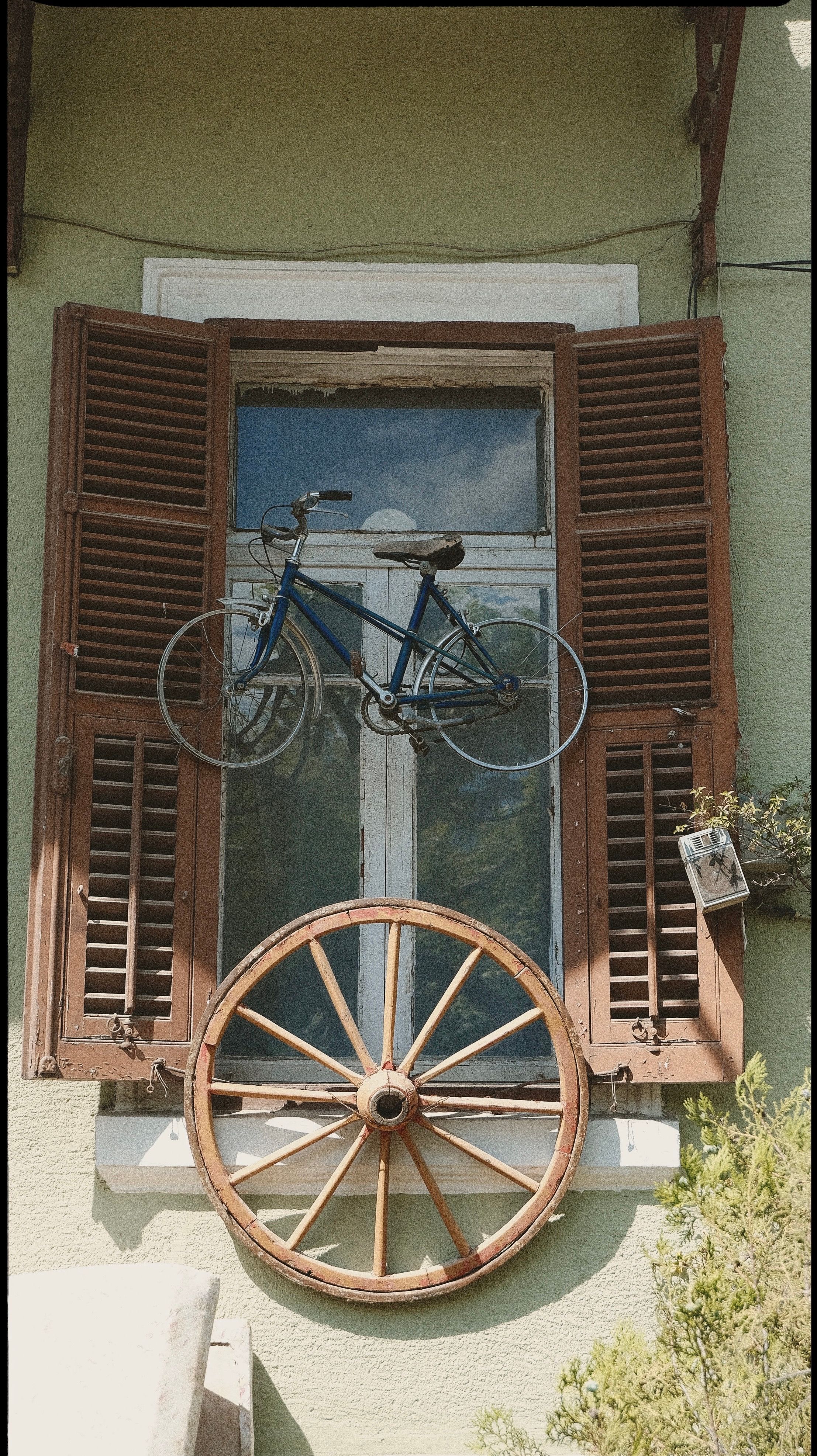 Vintage-style window with bicycle and wagon wheel decor creating a rustic charm.