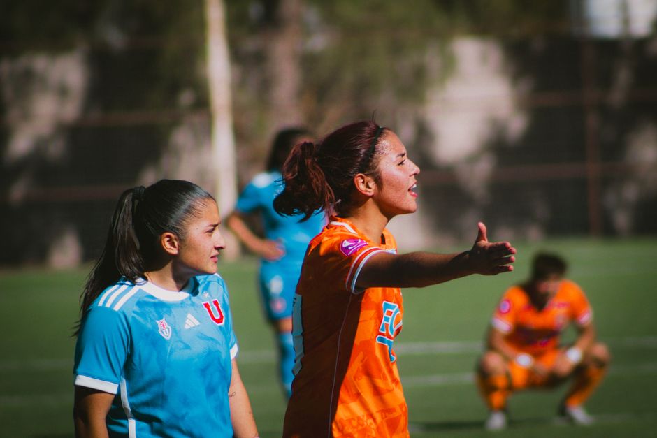 Female soccer players in action during a match in Calama, Chile, showcasing sportsmanship and teamwork.