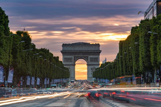 Sunset over Champs-Élysées with light trails and the iconic Arc de Triomphe in view.