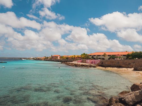Free Picturesque Caribbean beach with vibrant buildings along the coast under a clear blue sky. Stock Photo