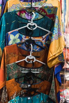 Vibrant traditional Vietnamese garments on hangers in a Hanoi market.
