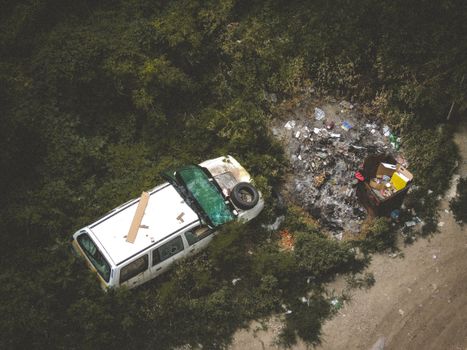 森林地区，一辆损坏的汽车和垃圾的俯视图，指示着污染和忽视