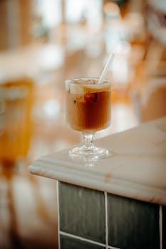A refreshing iced coffee served elegantly in a glass on a marble counter, perfect for a summer day.