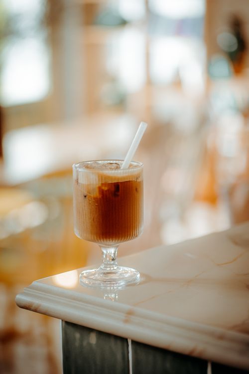 Free Close-up of iced coffee in elegant glass with straw on sunny day. Stock Photo