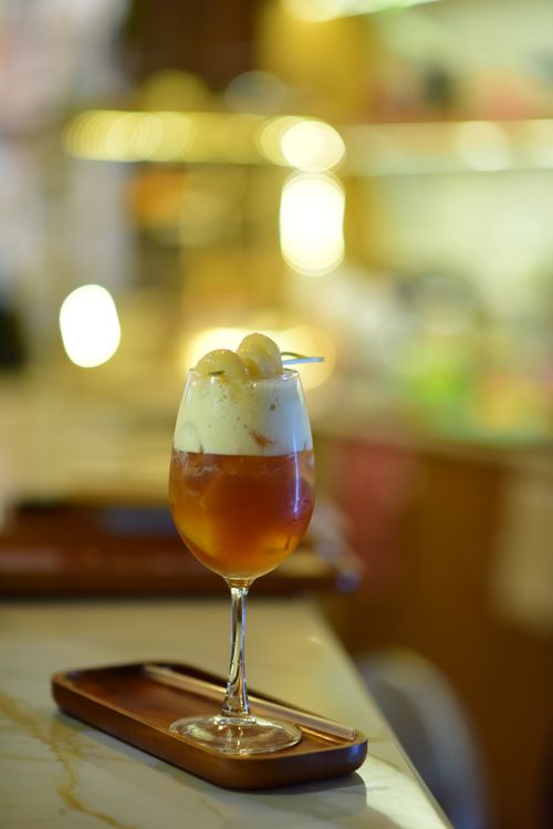 Free A sophisticated cocktail topped with foam served in a chic dimly lit bar setting, exuding an ambient warmth. Stock Photo