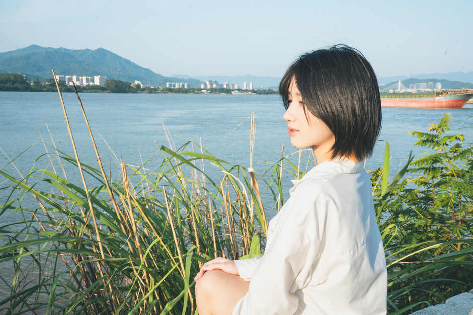 明るい日光の下で自然の景色を楽しむ女性と川辺での静かなひととき。