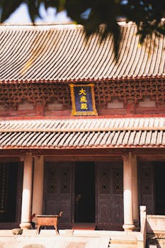 Sunlit view of a traditional Asian temple with ornate roof and entrance, showcasing cultural heritage.