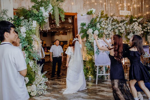 Bride entering decorated wedding venue with joyful guests and floral arrangements.