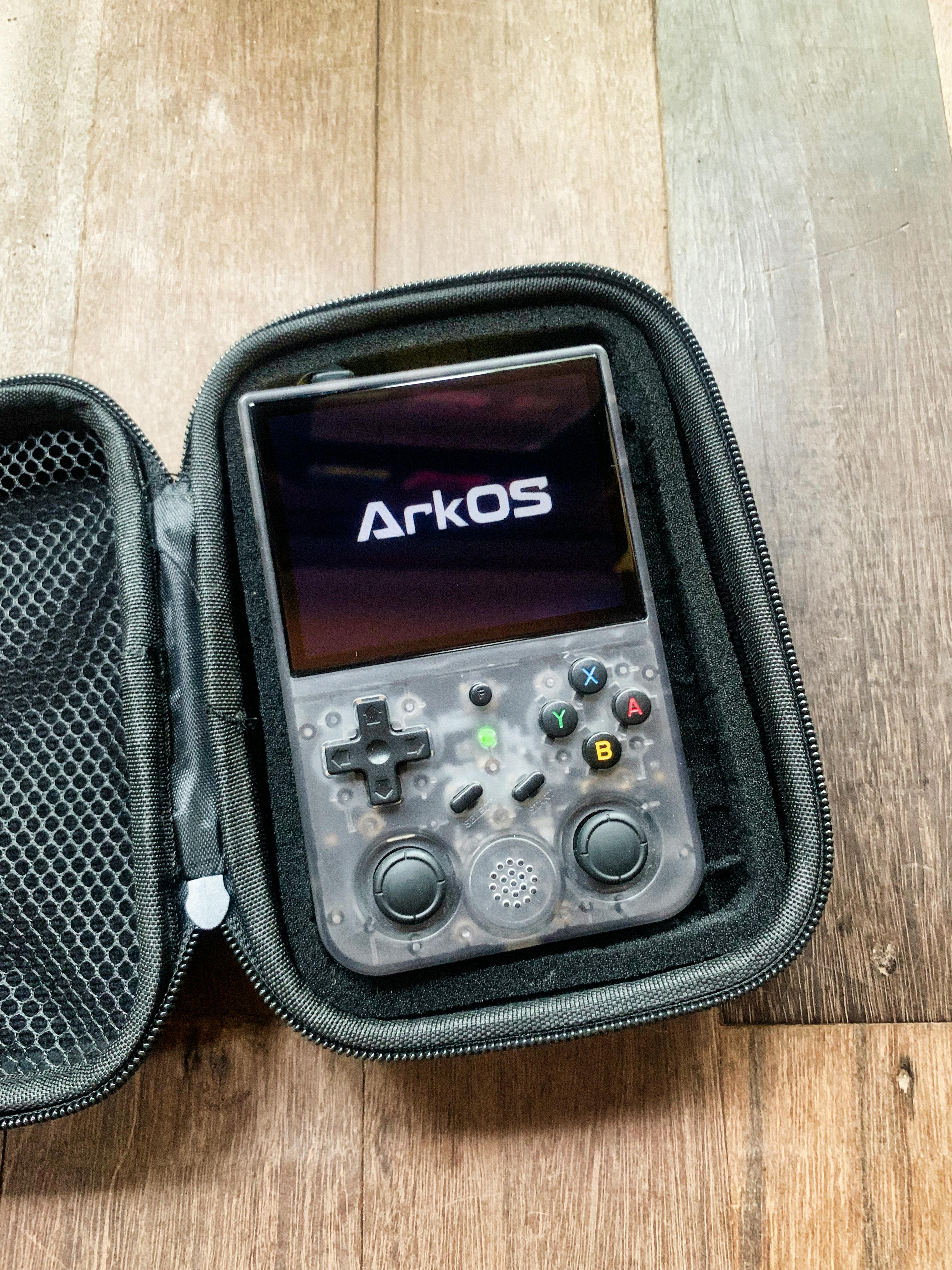 Close-up of a gaming console displaying ArkOS, showcasing buttons and controls in a hard case.