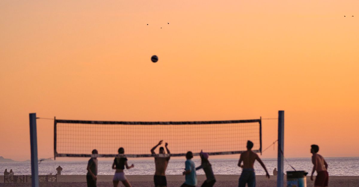 Rüyada Kardeşle Voleybol Oynamak - Rüya Tabiri ve Anlamı - Üzerinde bir uçağın uçtuğu canlı bir gün batımının altında plaj voleybolu oynayan insanların silüeti.