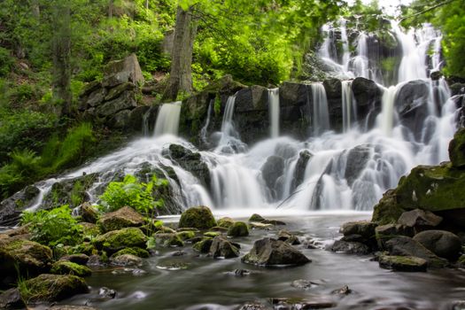 Captivating long exposure of a waterfall in Jönköping Län, Sweden surrounded by lush greenery.
