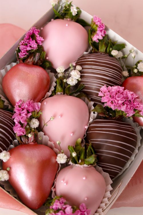 Free Elegant arrangement of assorted chocolate-covered strawberries adorned with flowers, perfect for gifting. Stock Photo