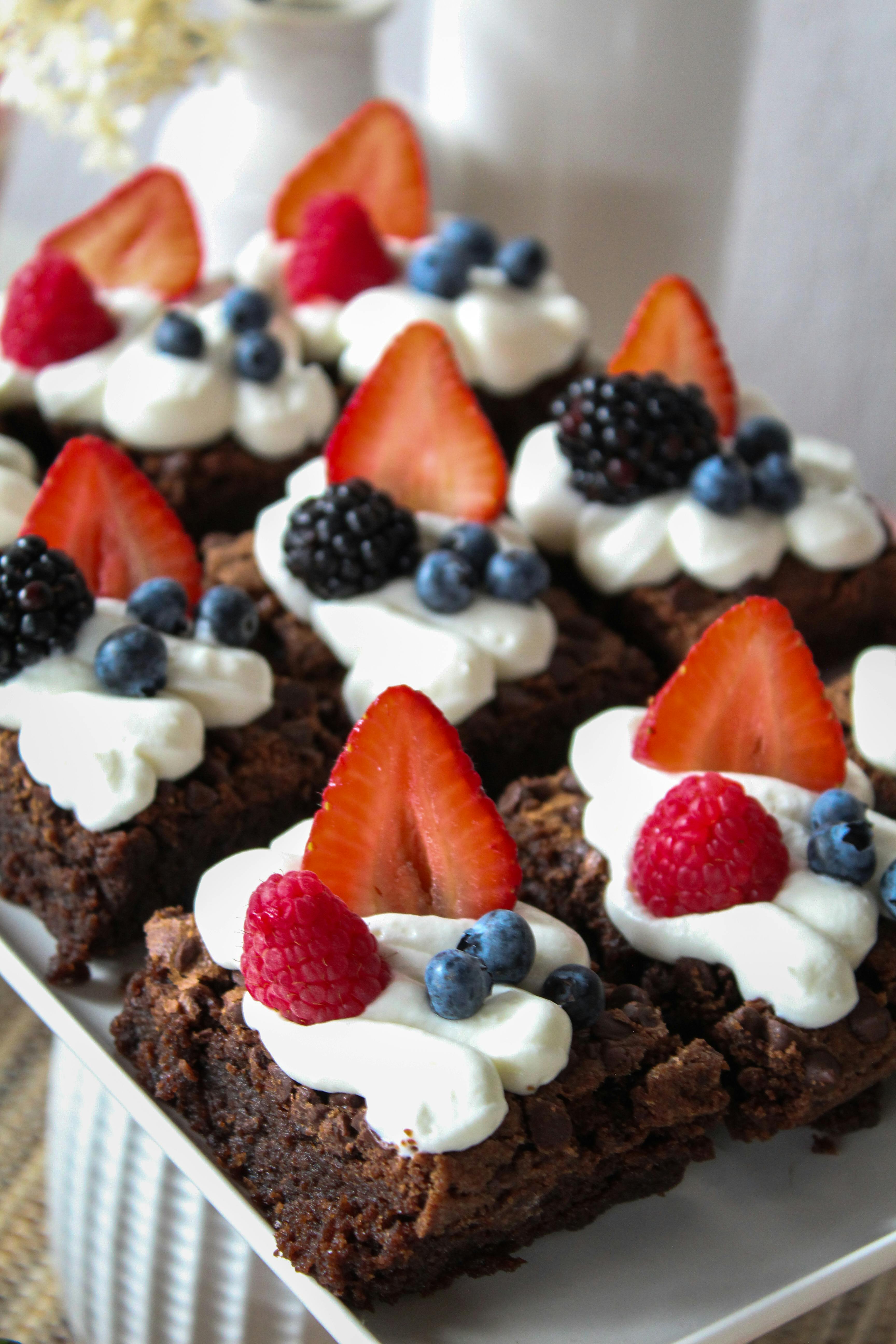 Mouthwatering chocolate brownies adorned with fresh berries and whipped cream for a delightful treat.
