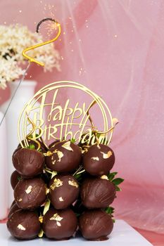 Chocolate truffle cake with gold accents and 'Happy Birthday' topper, perfect for celebrations.
