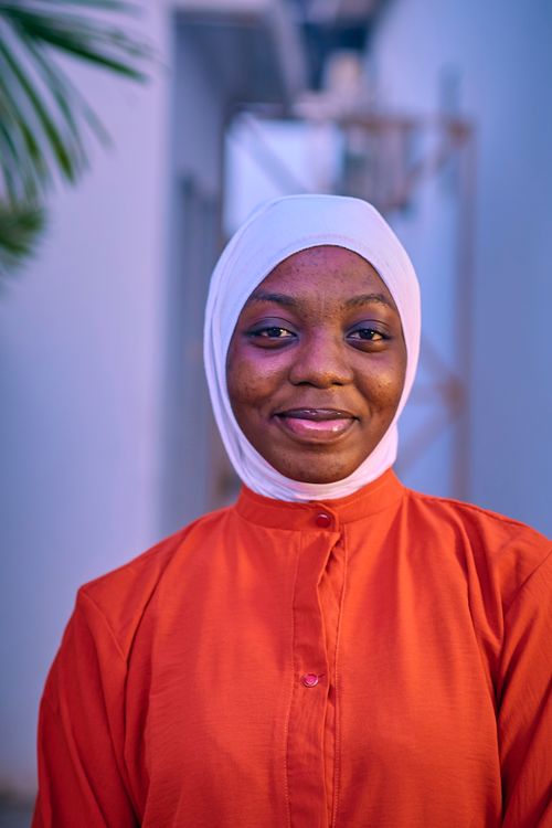 Free A joyful woman wearing an orange hijab and white underscarf, smiling indoors. Stock Photo