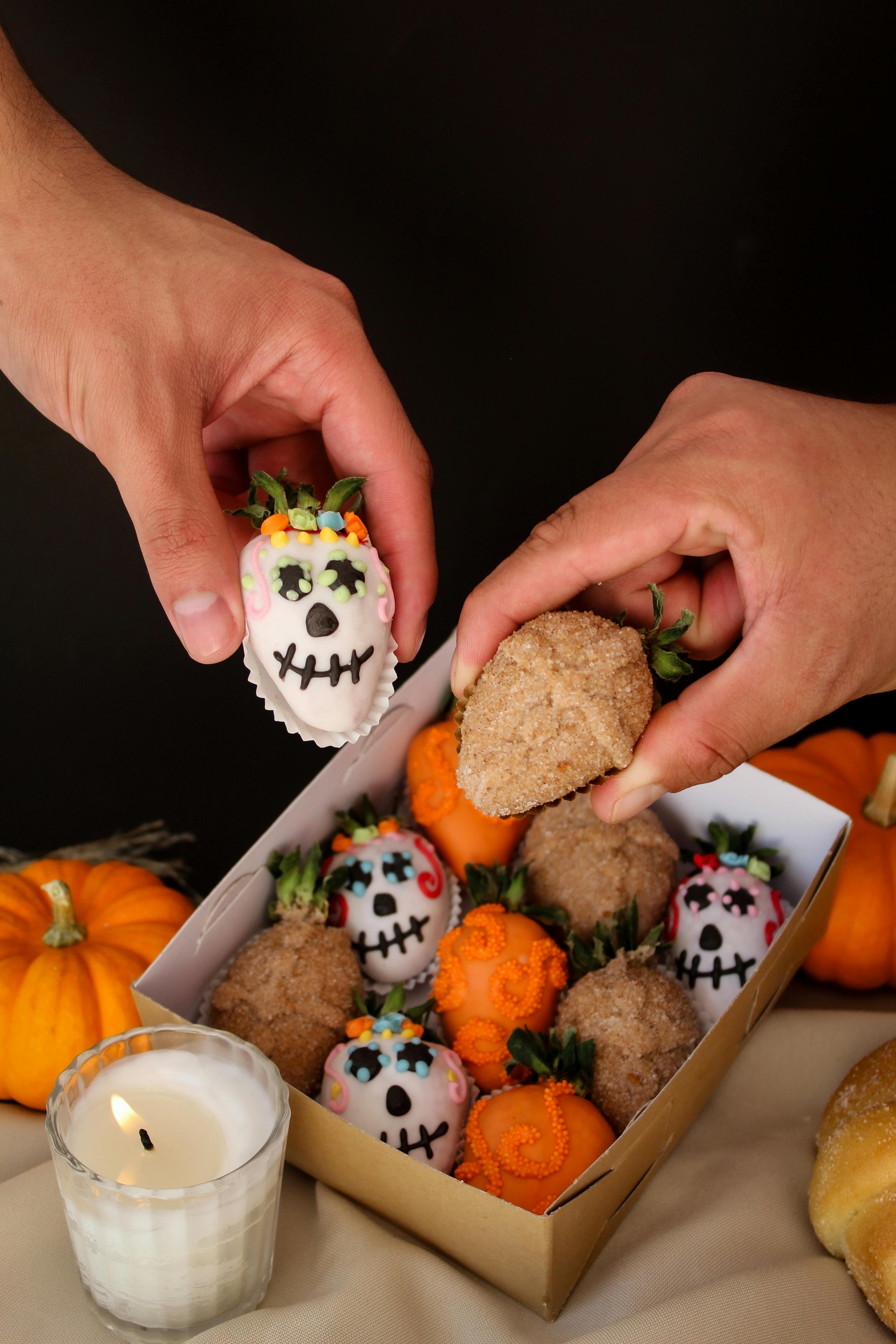 Halloween-themed decorated strawberries and pumpkins in a cozy setting.