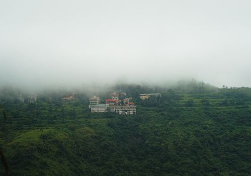A picturesque view of lush green hills and misty clouds in Mahabaleshwar, India.