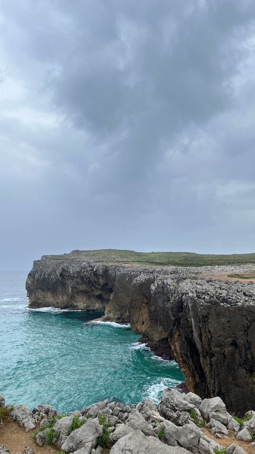 Free A stunning view of cliffs and ocean under a dramatic gray sky. Stock Photo