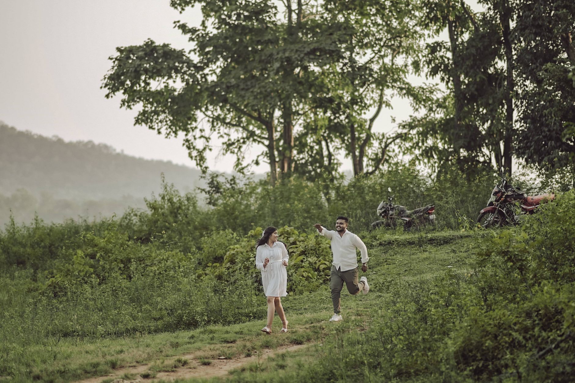A joyful couple enjoying a playful moment in a lush outdoor setting in Hubballi, Karnataka.