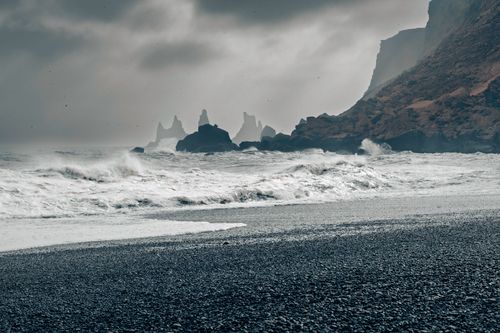 Free A dramatic view of Reynisfjara Beach with towering sea stacks in the distance. Stock Photo