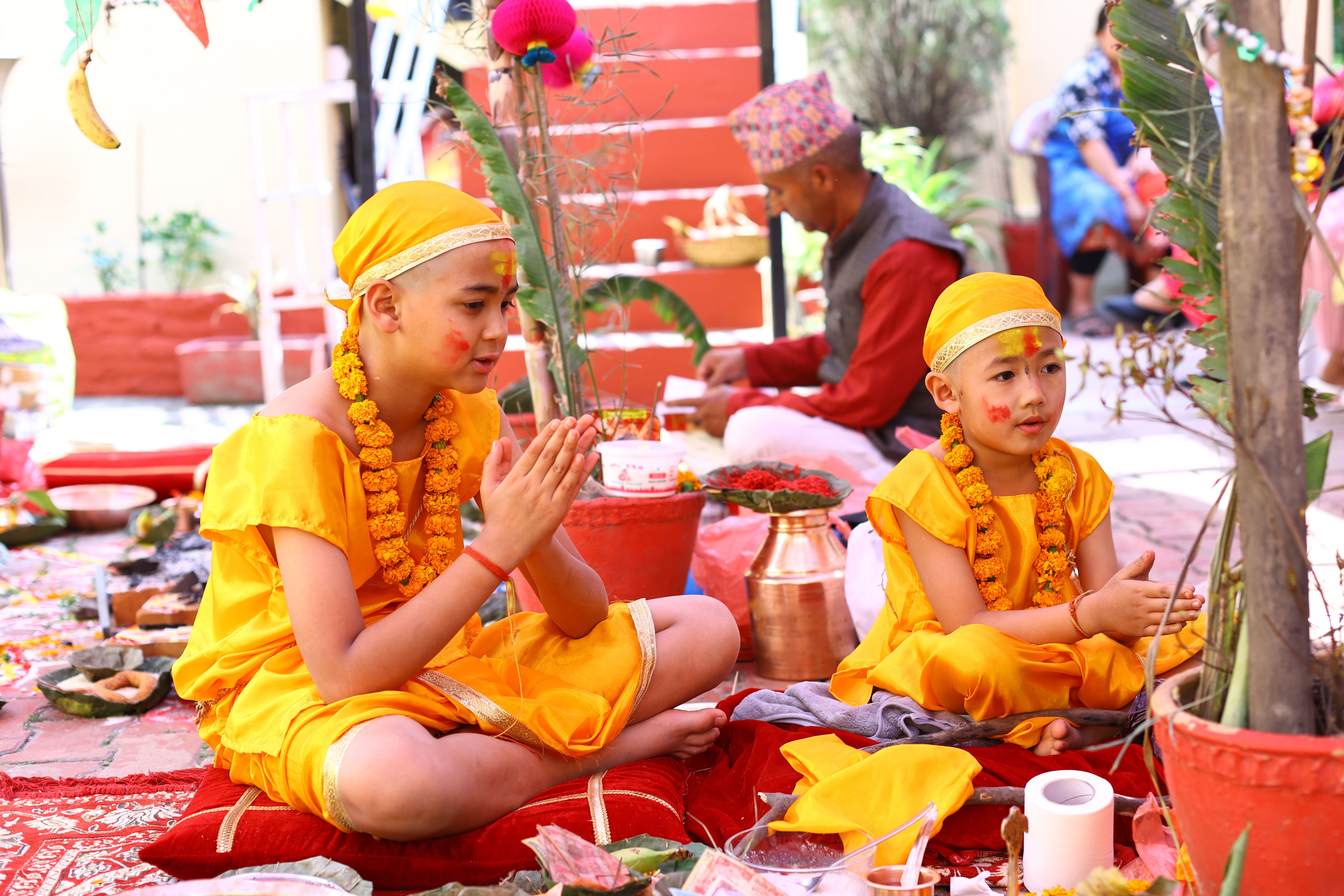 Children in yellow attire participate in a traditional Hindu ceremony with vibrant decorations.