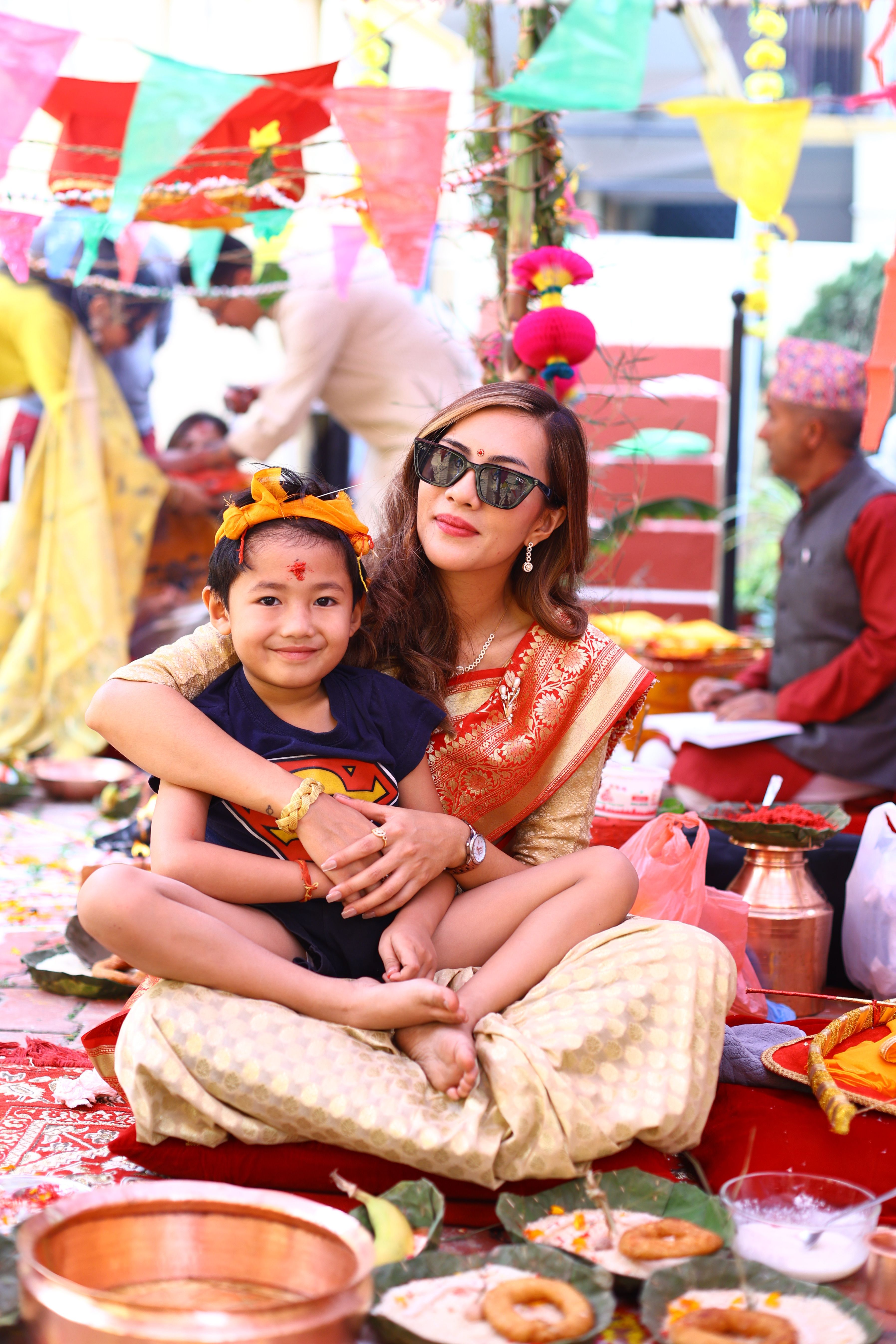 A joyful celebration of tradition with a mother and child in vibrant cultural clothing, surrounded by festive decorations.