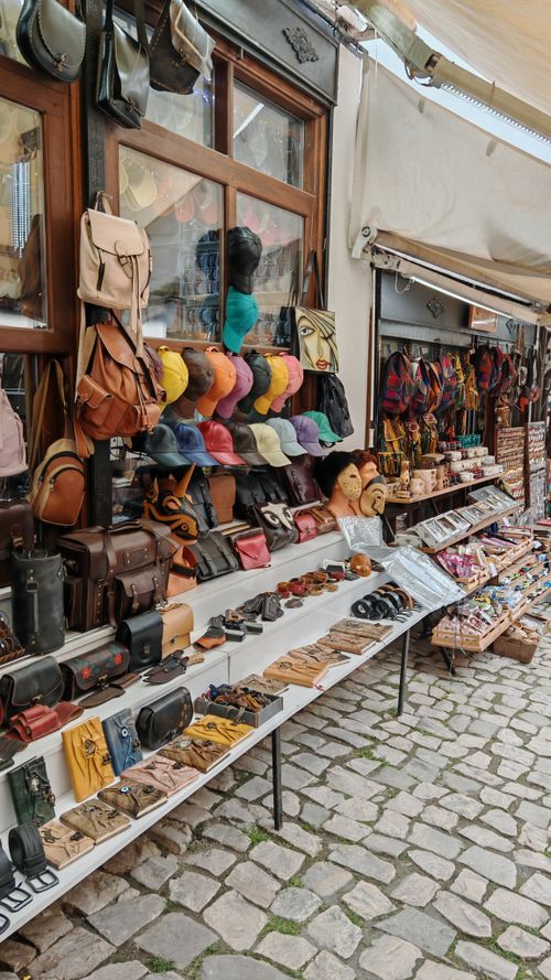Free Vibrant outdoor market stall with diverse leather accessories and caps on a cobbled street. Stock Photo